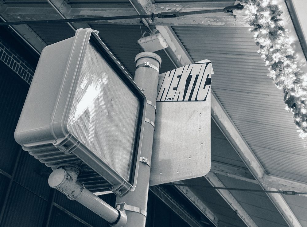 Crosswalk signal next to some Christmas lights 