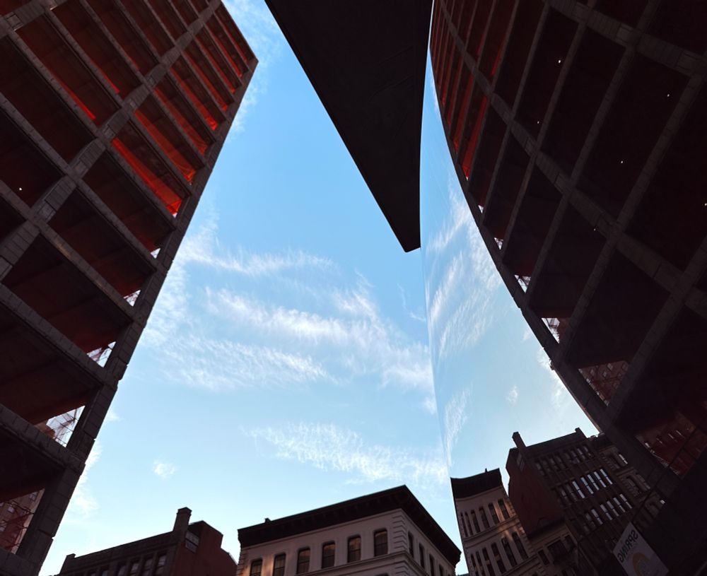 City buildings and sky reflecting on a polished convex metal surface 