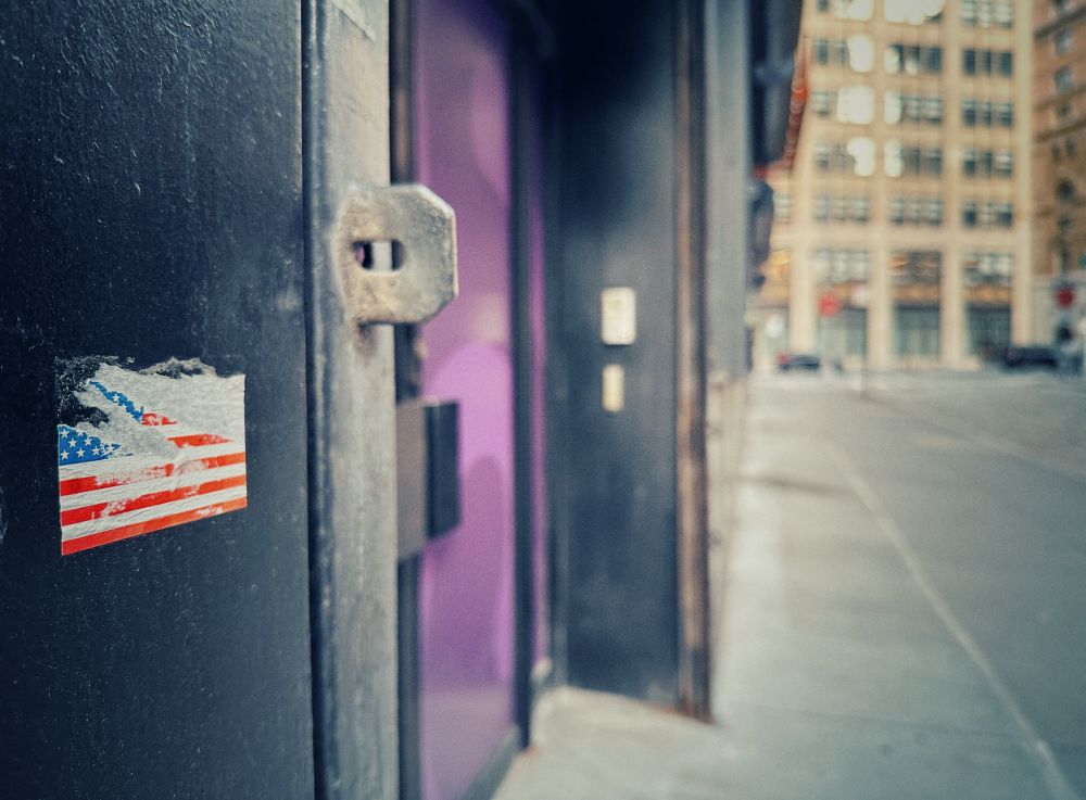A damaged and scratched American flag sticker on a building in nyc