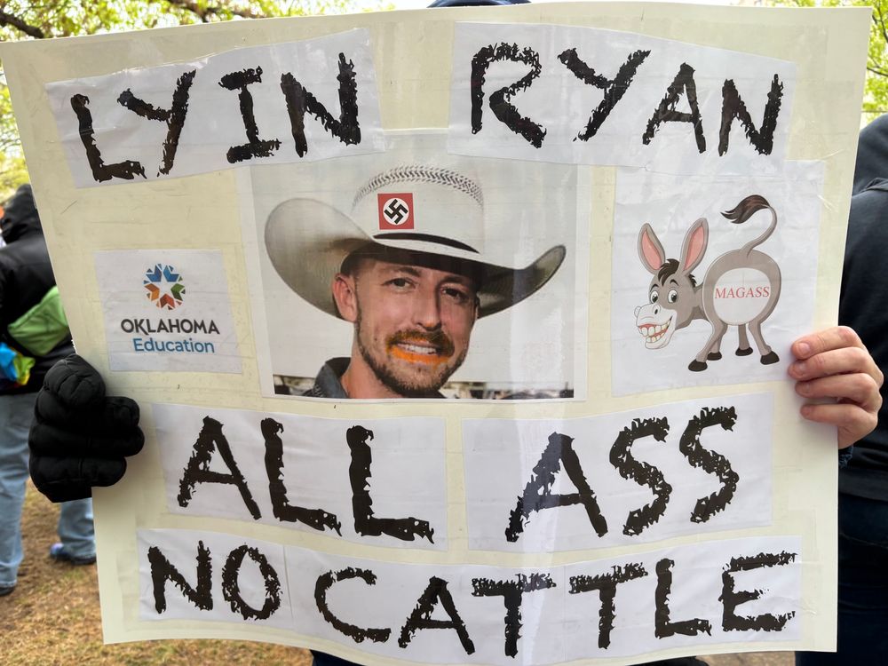 Protest sign with a photo of Oklahoma’s detested State Superintendent Ryan Walters wearing a cowboy hat with a swastika on it and with a picture of cartoon donkey with “Magass” written on its rear end. The sign reads “Lyin Ryan All Ass and No Cattle” (a play on the phrase “all hat and no cattle”)