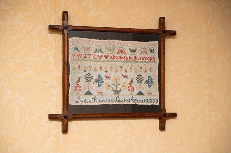 A piece of embroidery in a frame on a wall.