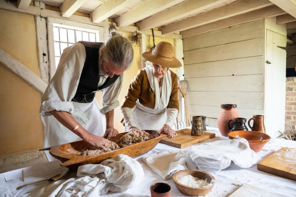 A man and woman needing dough in a cottage.