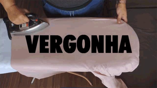 a person is ironing a shirt that has the word vergonha on it