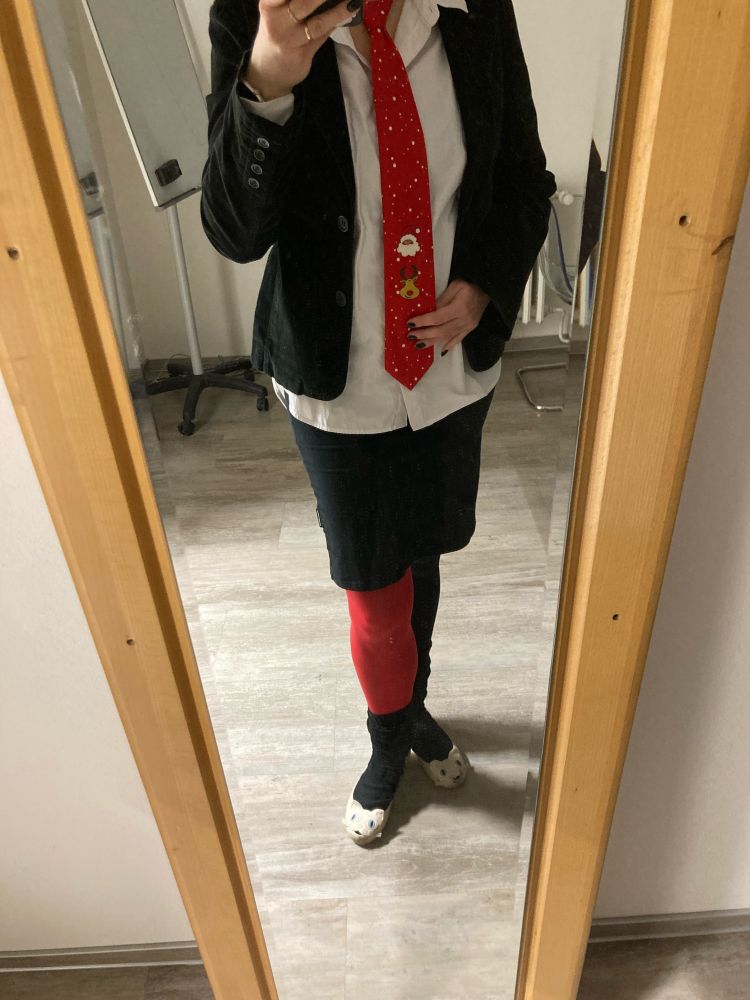 tacky christmass tie with what probably is Santa Claus and a reindeer complete with red nose, accompanied by red and black stockings, white shirt, and black skirt and jacket