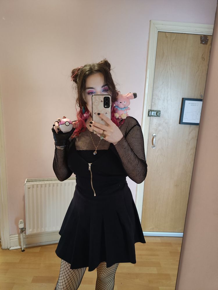 A girl with pink and brown hair holding a pink pokeball with a Snubbull plushie