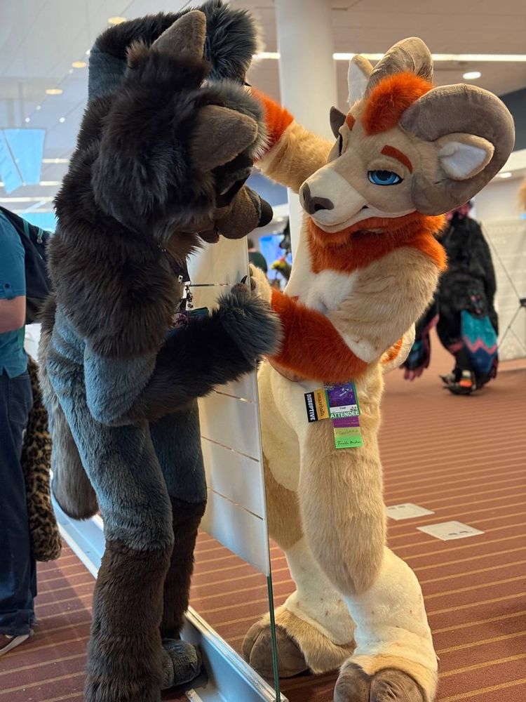 Faar and Alloy playing around in suit looking around a wall like they are each others reflections. 
