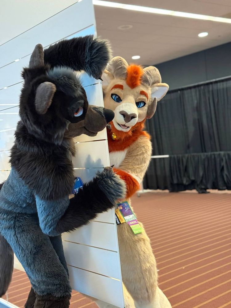 Faar and Alloy playing around in suit looking around a wall like they are each others reflections. 