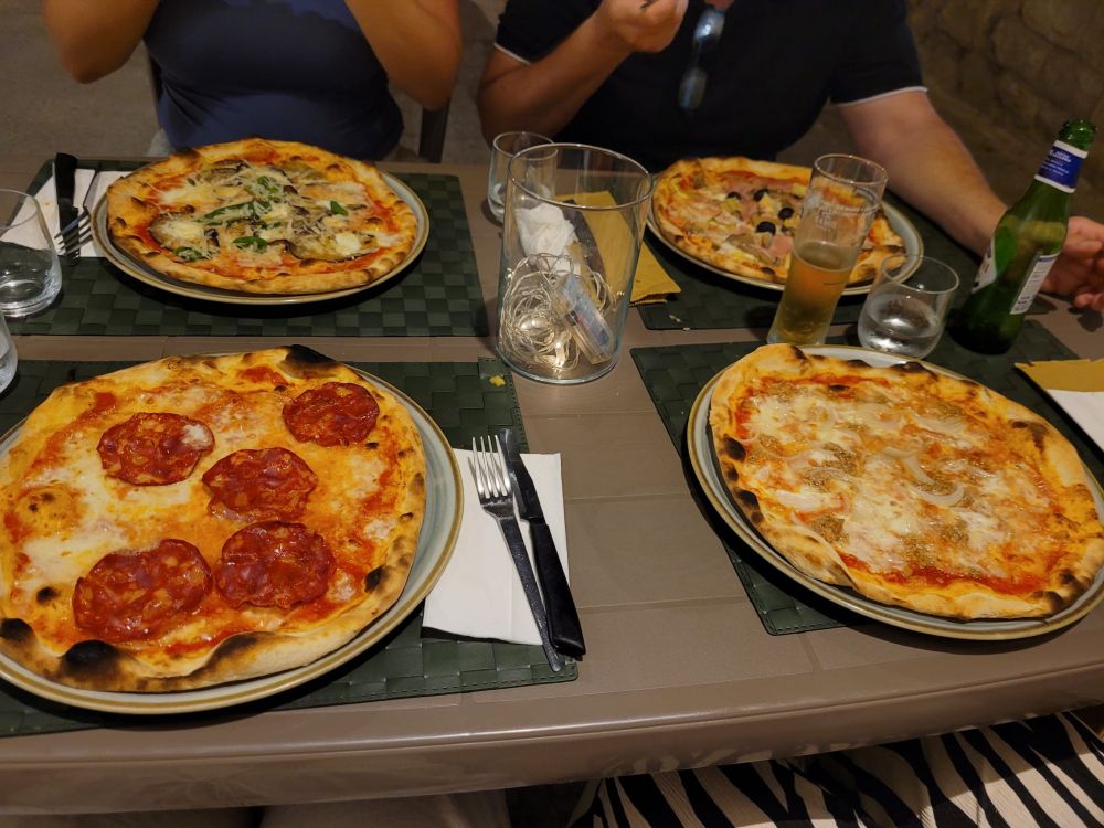 Ein gedeckter Tisch mit 4 verschiedenen Pizzen und Getränken