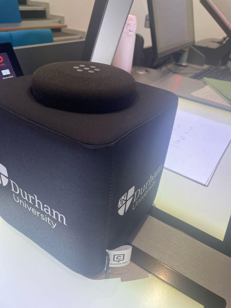 A soft black cube, about 6” on each side, with Durham university branding. It’s plonked in between two visualisers on the lecture desk. 