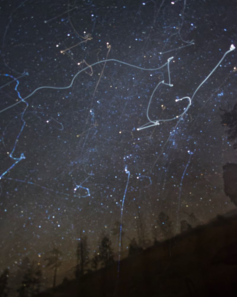 A photo of the constellation Orion over a silhouetted landscape, in which the stars are doubled and the brighter ones have streaks of light coming off them from accidental motion of the tripod during the exposure