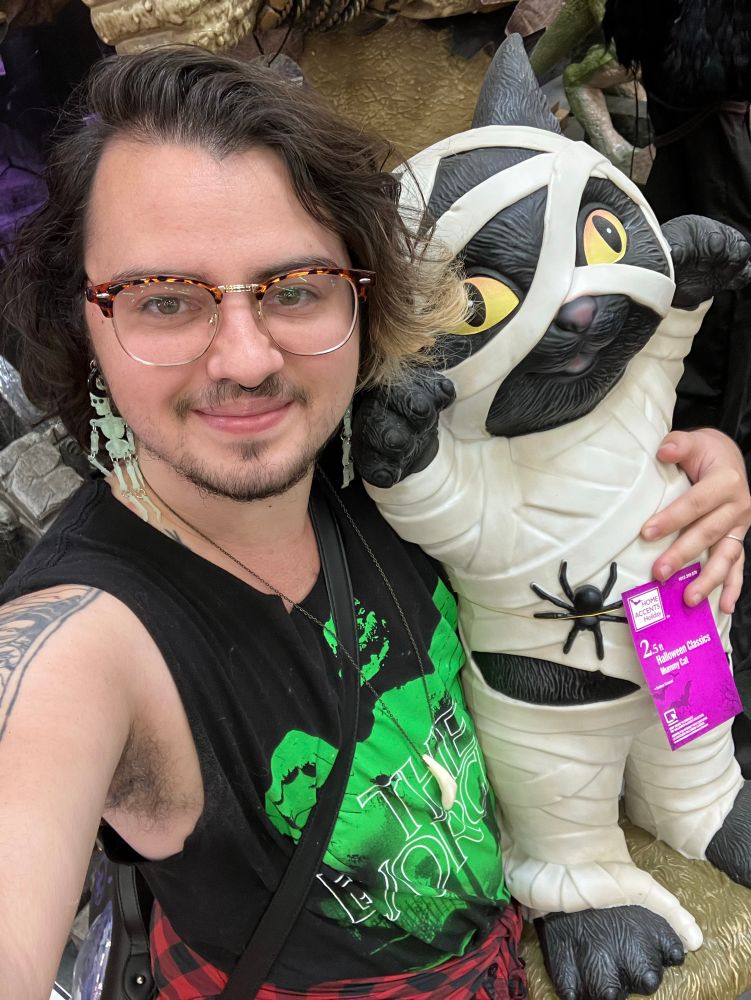 The artist holding a 2ft statue of a cat dressed as a mummy