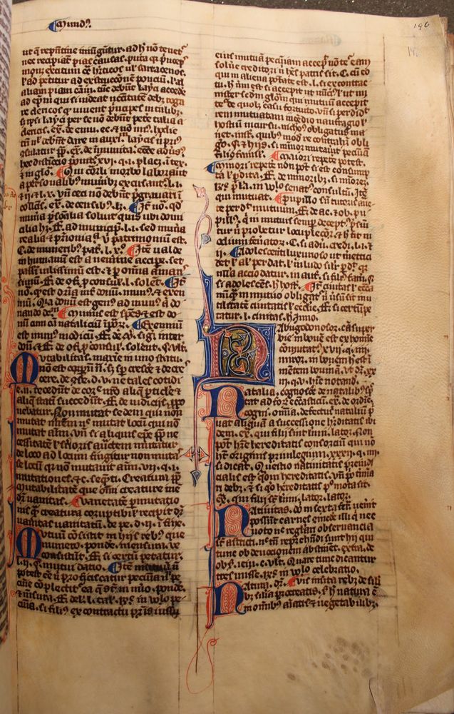 A burgundy illuminated letter N with a navy blue background is at the midway point in the right hand column of text in this law book. The letter has foliage drawn spouting from the top and bottom of it. In the centre of the letter N is blue foliage with blue or red leaves and gold background. New paragraphs also start with a smaller blue capital letter with red and white infilling.