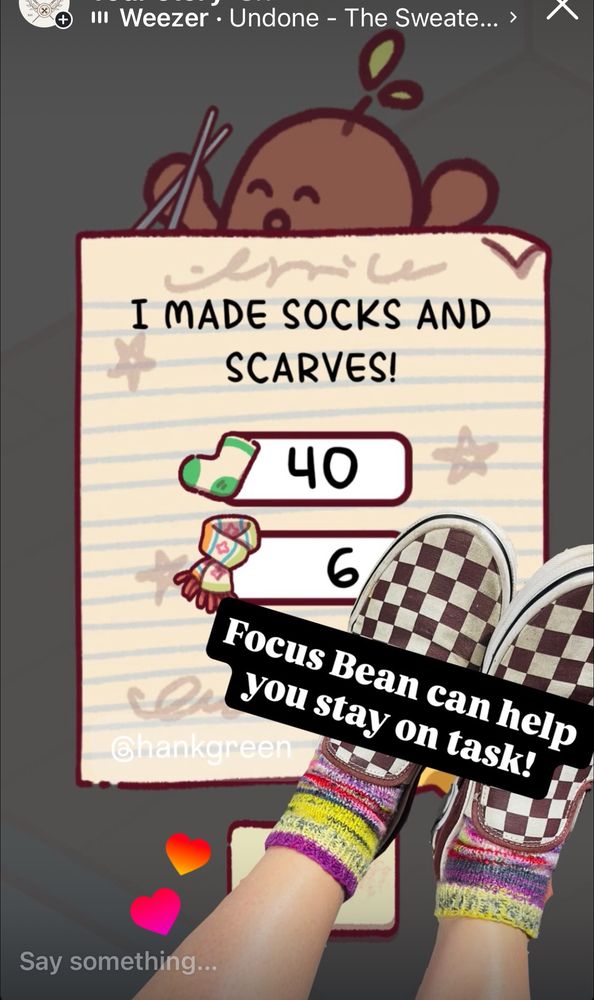A screen shot of the focus friends app bean tallying my socks (40) and scarves (6) my bean knit in the app, and a cut out image of my hand knit socks knit in varying shades of bright yellow, pinks, reds and specks of black. I’m wearing brown checkered van creeper style shoes. Tagged is the song Undone by Weezer. 