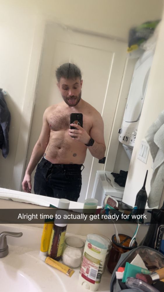 Average white guy wearing black pants and no t-shirt in front of a bathroom mirror 