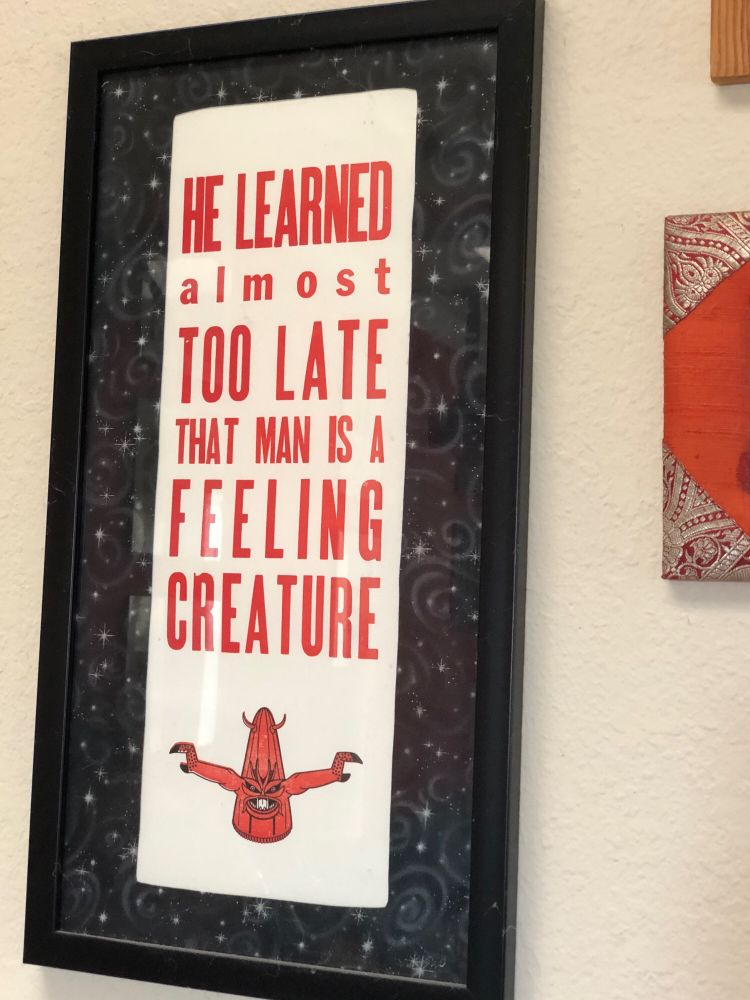 A print that says “He learned almost too late that man is a feeling creature,” a quote from “It Conquered the World,” with a drawing of Beulah the carrot monster.