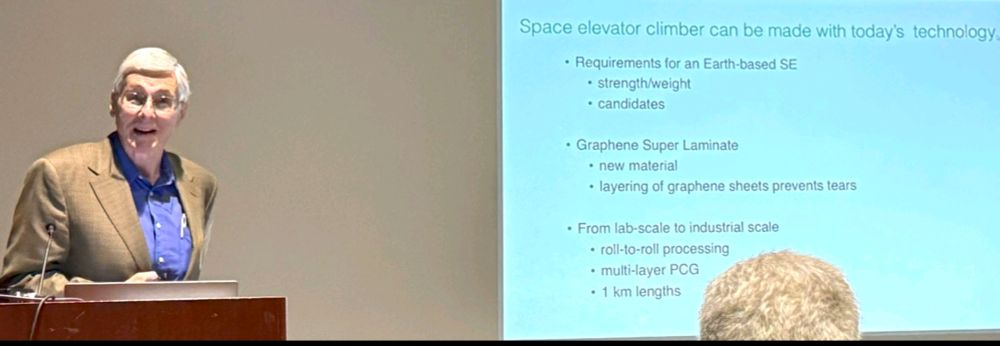 Photo of speaker and slide.
Text as follows :

Space elevator climber can be made with today’s technology
• Requirements for an Earth-based SE
• strength/weight
• candidates 
• Graphene Super Laminate 
• new material
• layering of graphene sheets prevents tears 
• From lab-scale to industrial scale 
• roll-to-roll processing 
• multi-layer PCG
1 km lengths 