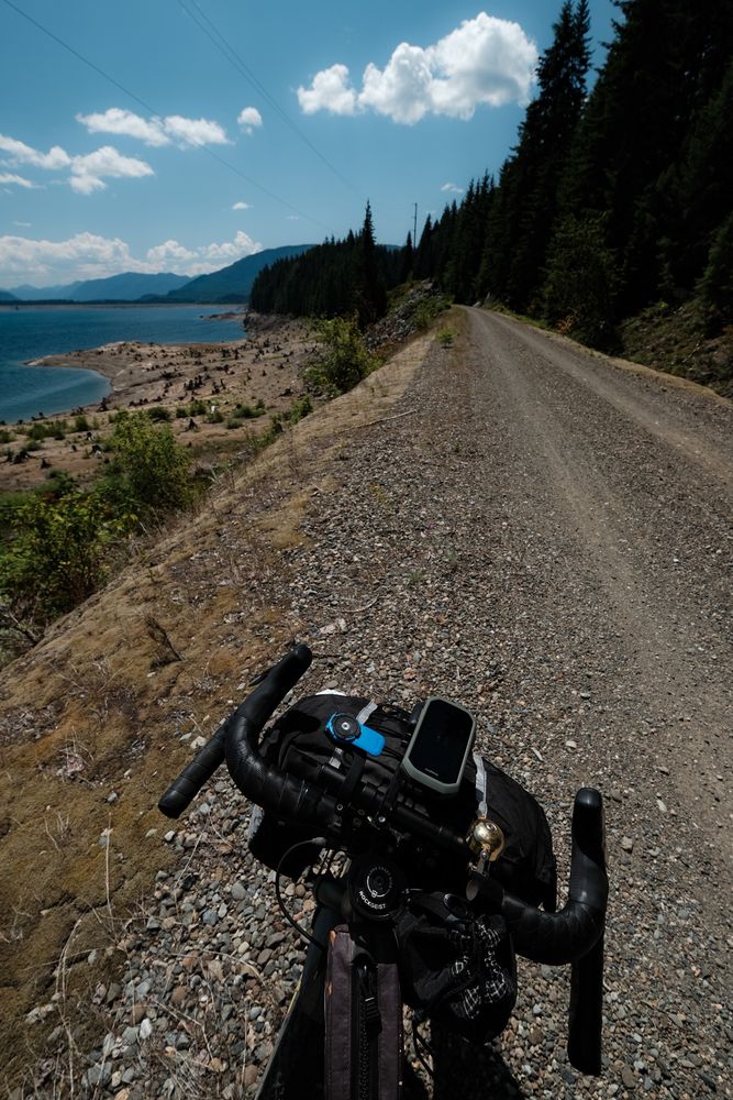 I am sitting on my bike next to Kachess Lake. The lake is blue and so is the sky although there are some cottony clouds 