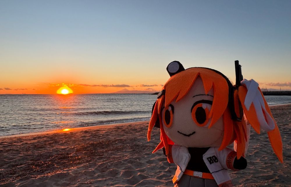 冬のビーチ。足立ぬいはまもなく日没の太陽を見つめる。太陽の隣には富士山が映っている。
(Winter beach.Stuffed Adachi is looking at the soon-to-be-set sun.Next to the sun is Mt. Fuji)