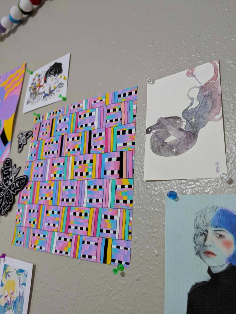 A series of art prints on my office wall. Closest there's a Patreon original from Rincs. An ethereal femme person with knees tucked to chest and arms wrapped around the shins, with long hair outstretched and flowing and a constellation of stars across various points of the body.

It's surrounded by other pieces: A blue-hued portrait by minimalista; an abstract, vibrant, color block piece by studiomucci; a towering person overlooking a tiny carnival by milkytomato; Femme & Flora 1: Lavender Lady by Rincs (a blonde woman floating in water with lavender sprigs everywhere); and two black moth & mothman patches by harvey nissen.