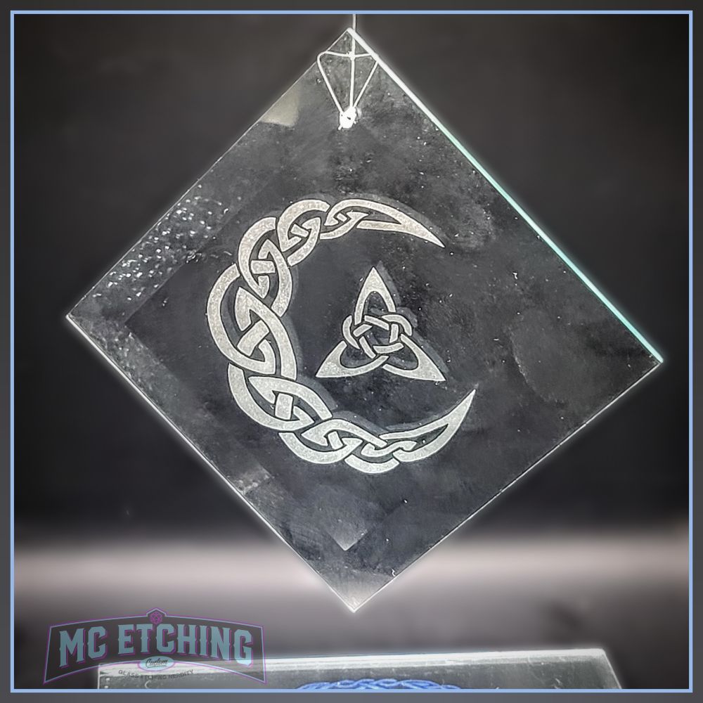product photo of a diamond shaped glass suncatcher  etched with a knotwork crescent moon and triquetra design