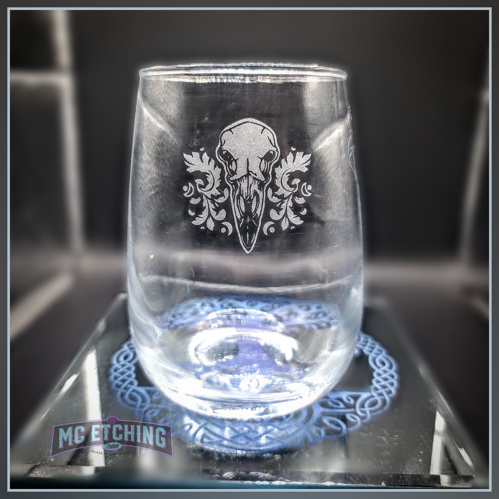 Stemless wine glass etched with a ravens skull and leafy scrollwork