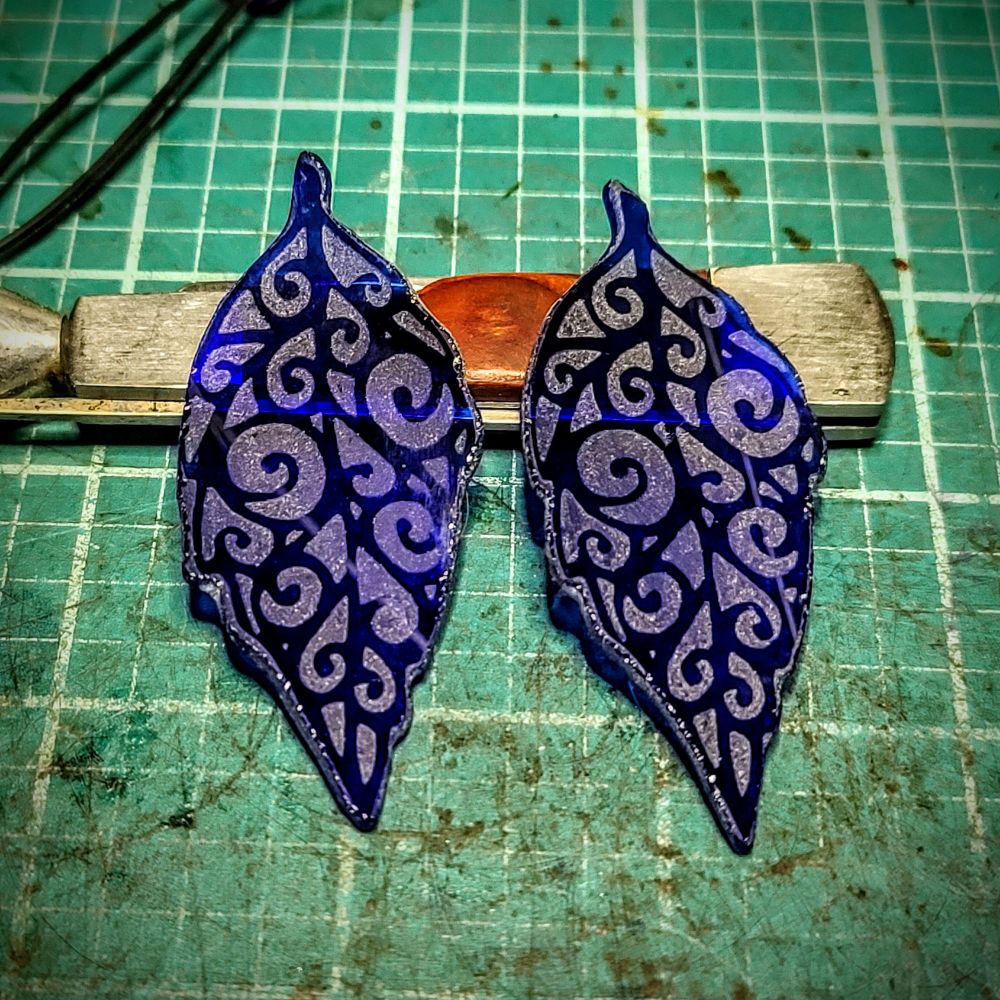 two filigree etched pieces of cobalt blue glass shaped to look like leaves