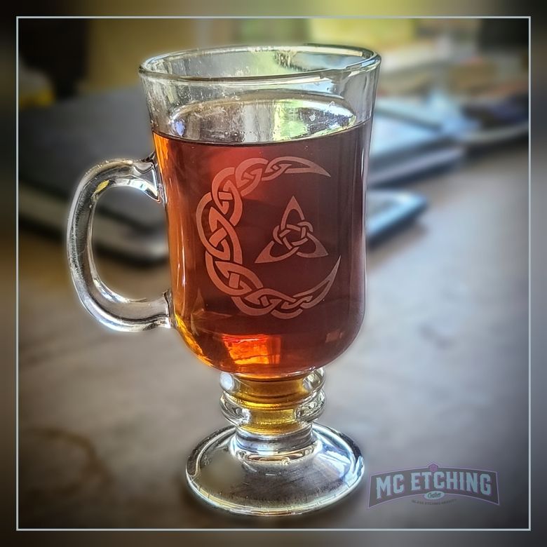 product photo of an Irish coffee mug filled with tea and etched with a knotwork crescent moon and triquetra design