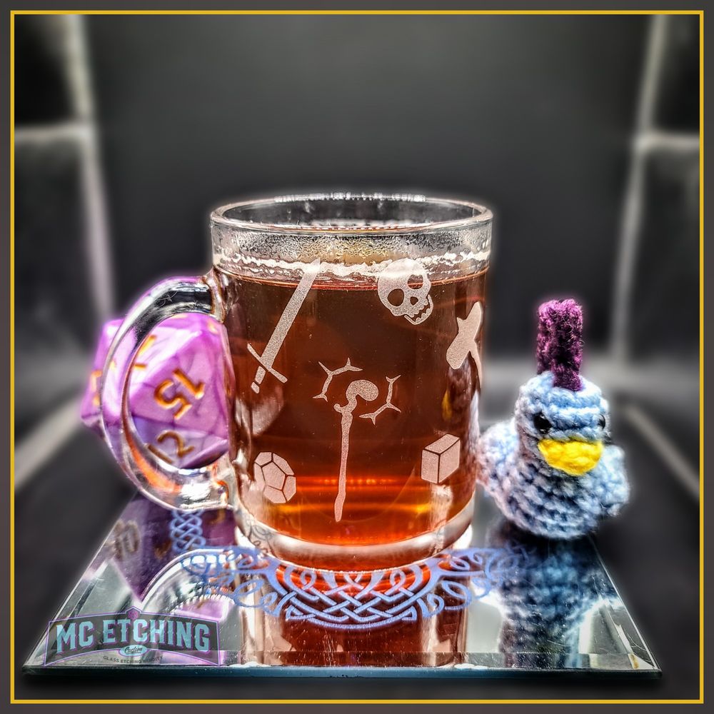 Glass mug etched with various fantasy weapons like swords, axes and a wizards staff along with polyhedral gaming dice shapes