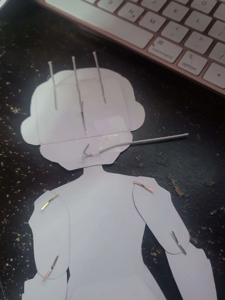 The neck of the body going through the head slit and bent wire through the neck hole. The longer end is on the tape