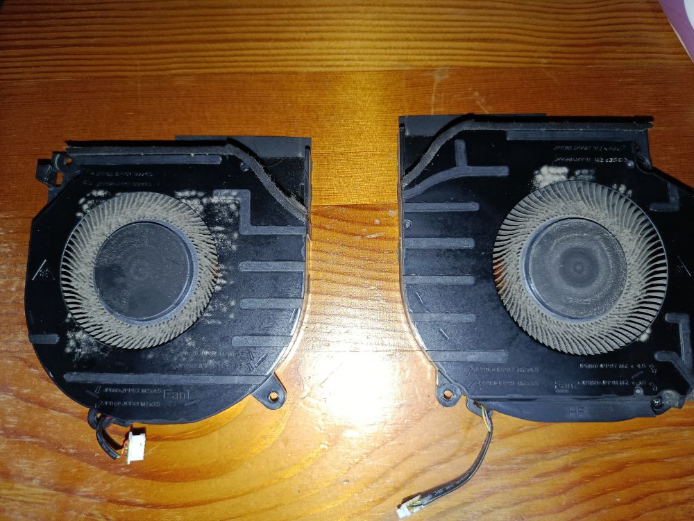 A close up photo of two laptop fans on a table. They are very dusty.