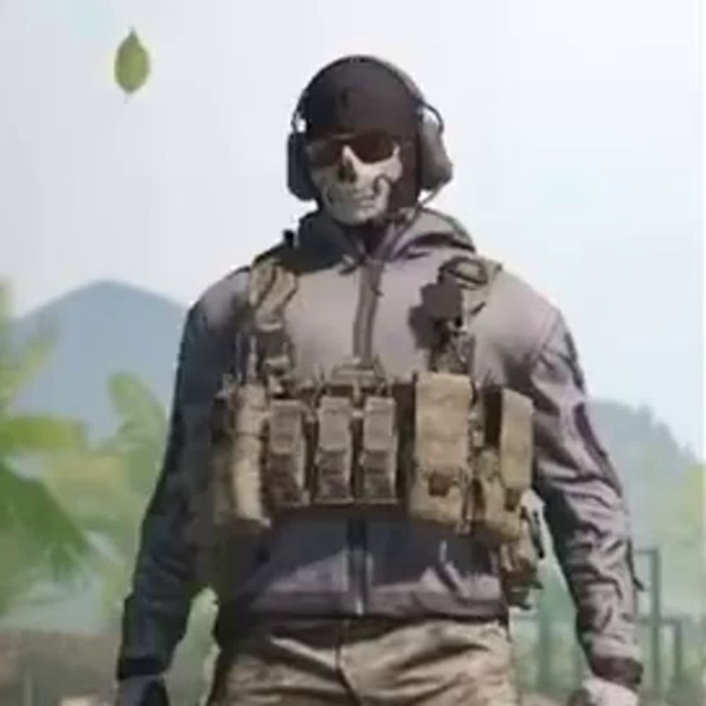 a soldier with a skull mask and headphones is standing in a field .