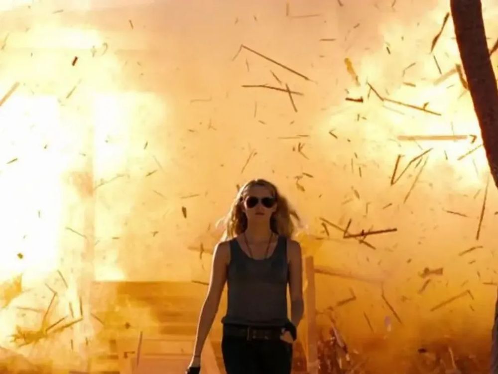 Woman walking away from a fiery inferno