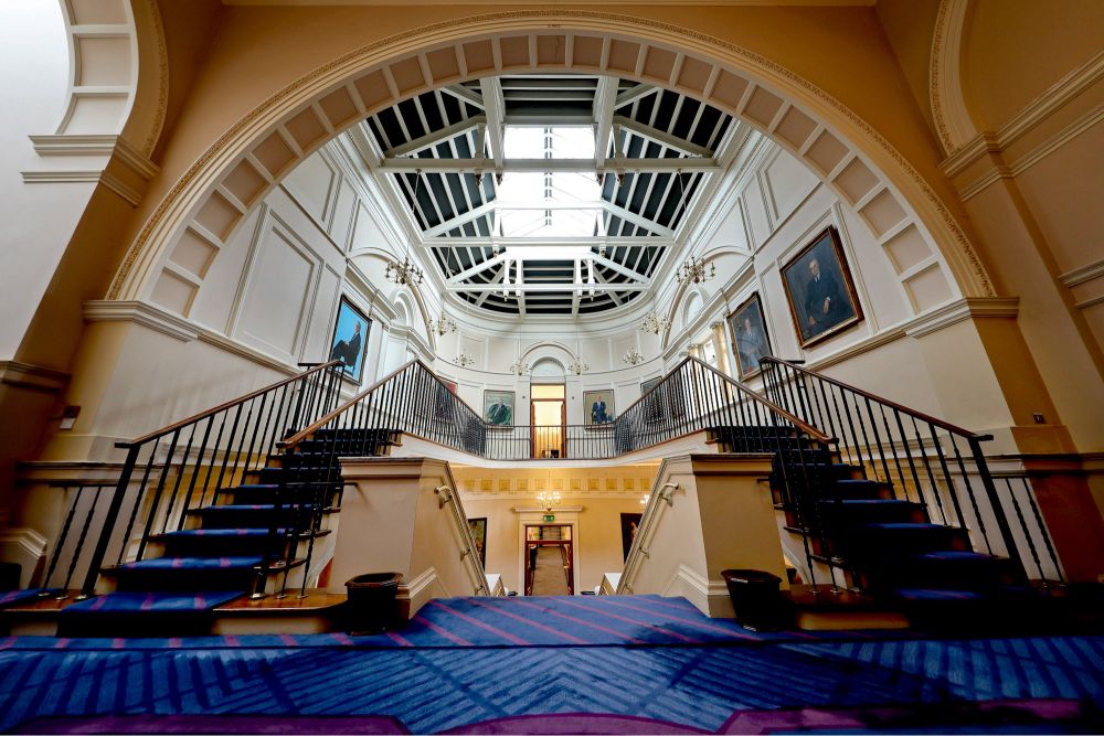 An image of the main staircase, taken from the perspective of leaving the Dáil Chamber. The image includes the Taoiseach’s Gallery, where portraits of former Taoisigh are on display.