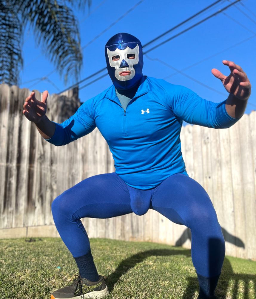 guy dressed as the blue demon luchador striking a wrestling pose outside