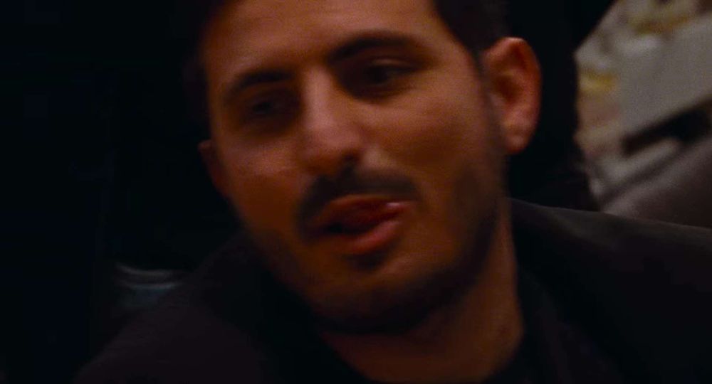 Image prise à 11 minutes et 11 secondes du film A Chiara.

Au centre et en gros plan, un homme est souriant, sa langue passant entre ses lèvres pour accentuer son air de contentement. Il a une moustache, des cheveux bruns et c'est plutôt le beau gosse.