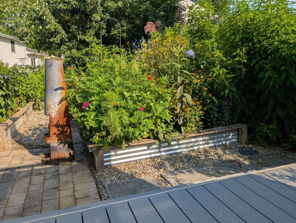 Flower bed in backyard garden with outdoor fireplace and patio.