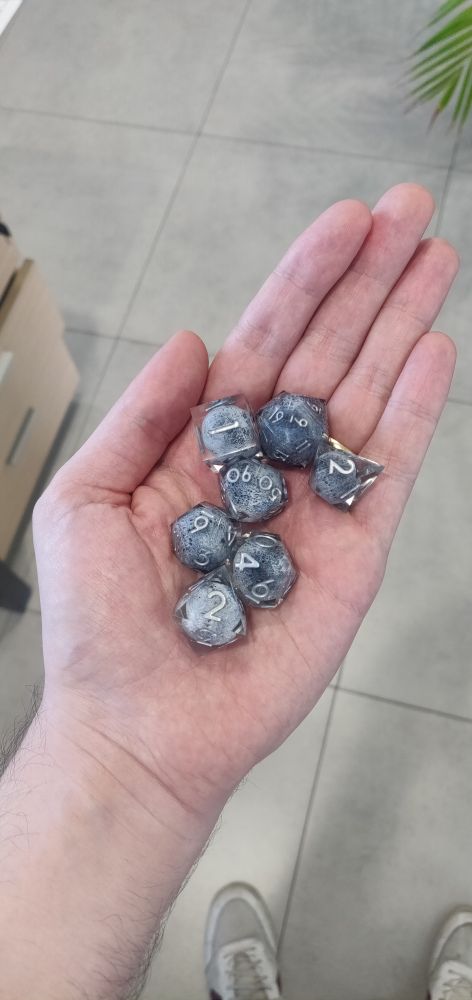 Foto de mi mano con mi set de dados para jugar al rol personalizados con lunas dentro que me regalaron mis amigos porque son los mejores 