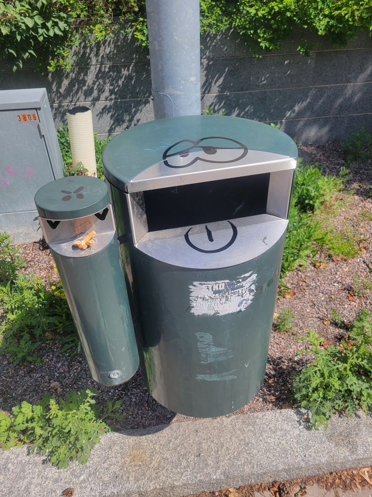 Graffiti of cartoon faces on a trash can and ashtray