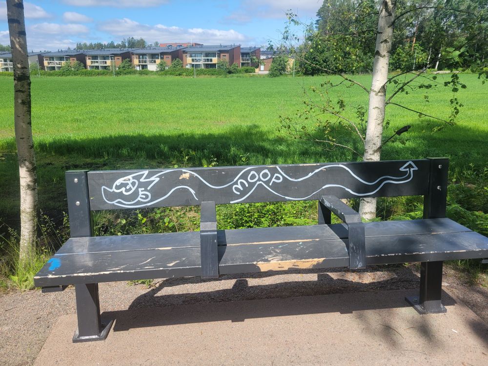 Graffiti of a wyrm-like thing on a bench