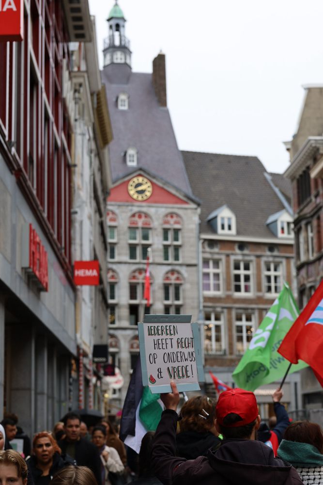 protest march through the inner city of Maastricht: union flags and hats in front of the old Dutch houses. Also pictured a protest sign (in Dutch) that translates to “everyone has a right to education and peace”