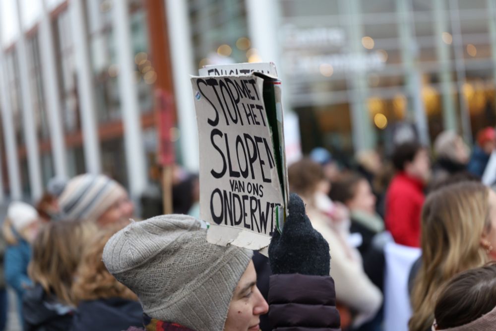 Protesters, more protesters, the blurred facade of Centre Ceramique - housing Maastricht's city library - and a sign that says "stop met het slopen van ons onderwijs" (stop wreaking our education)