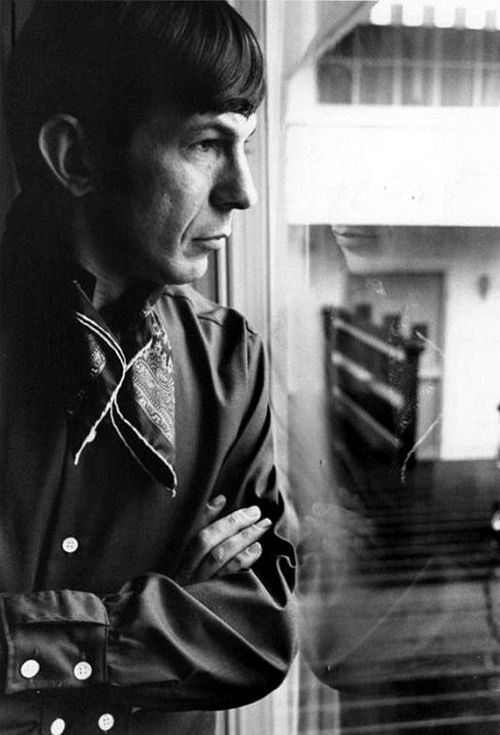 Black and white photograph of Leonard Nimoy with his arms crossed and looking out of a window. Star Trek actor.