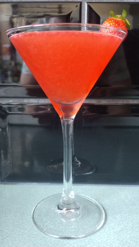 A pink Strawberry Daiquiri in a Martini glass, garnished with a strawberry on the rim.