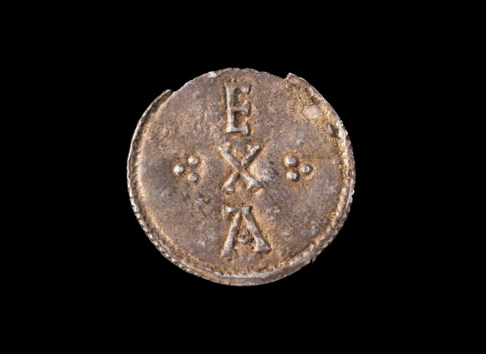 a tarnished penny bearing the lettering E X A arranged vertically