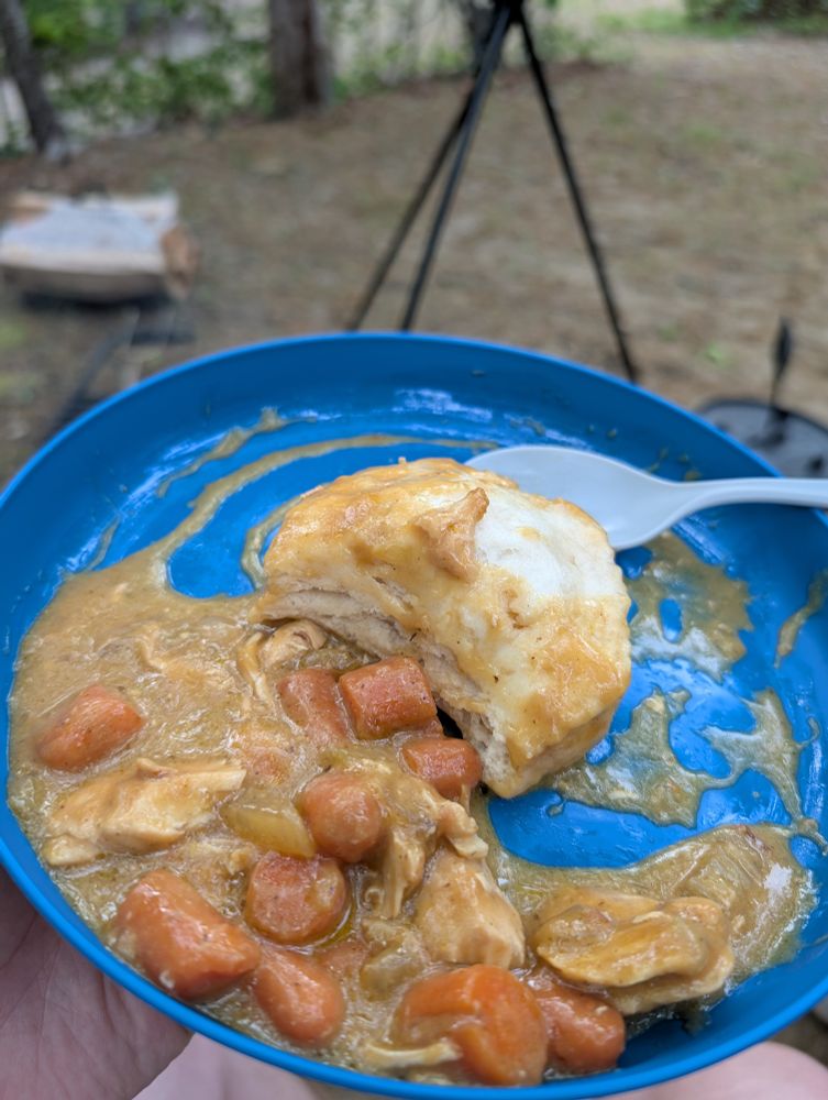 The finished dish is half eaten on a blue plate. Part of the cooked biscuit is visible with the delicious sauce, chicken, and vegetables.