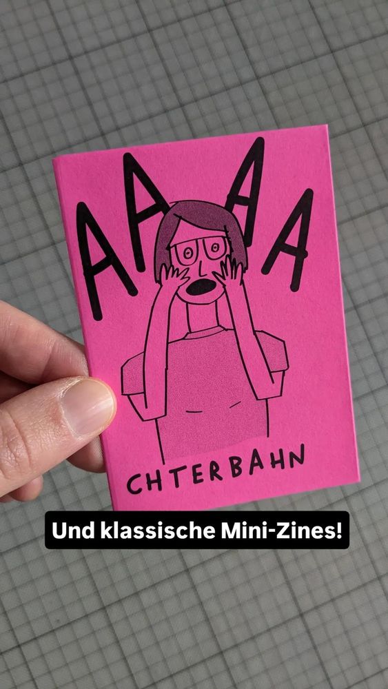 Ein pinkes kleines Heft mit einer Illustration einer schreienden Person mit Überschrift Aaaachterbahn