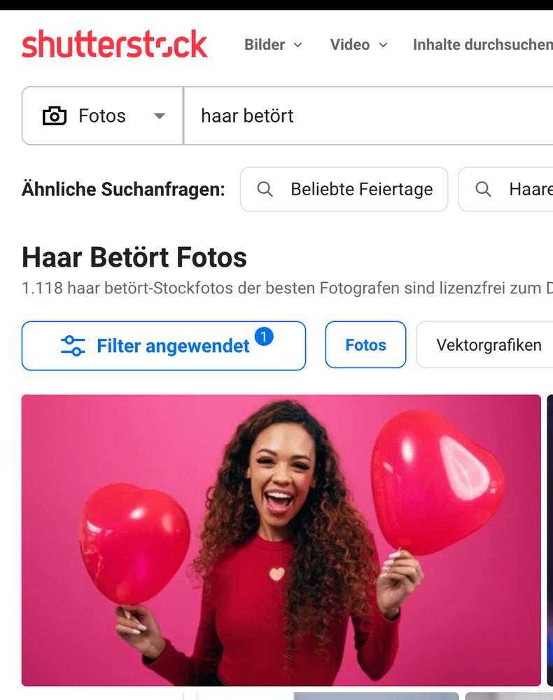 Screenshot von Shutterstock Suchergebnis zum Begriff "Haar betört"; Suchergebnis ist eine Frau die zwei rote Herzluftballons in den Händen hält