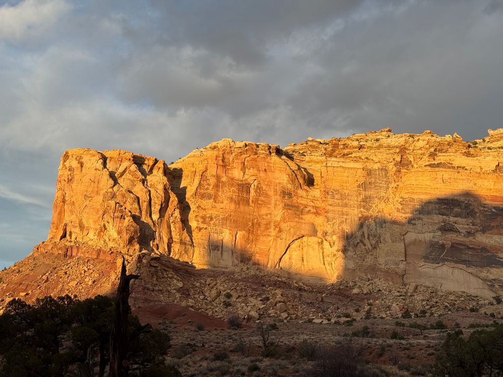 View of a rock cliff at sunset with a moody sky above. 