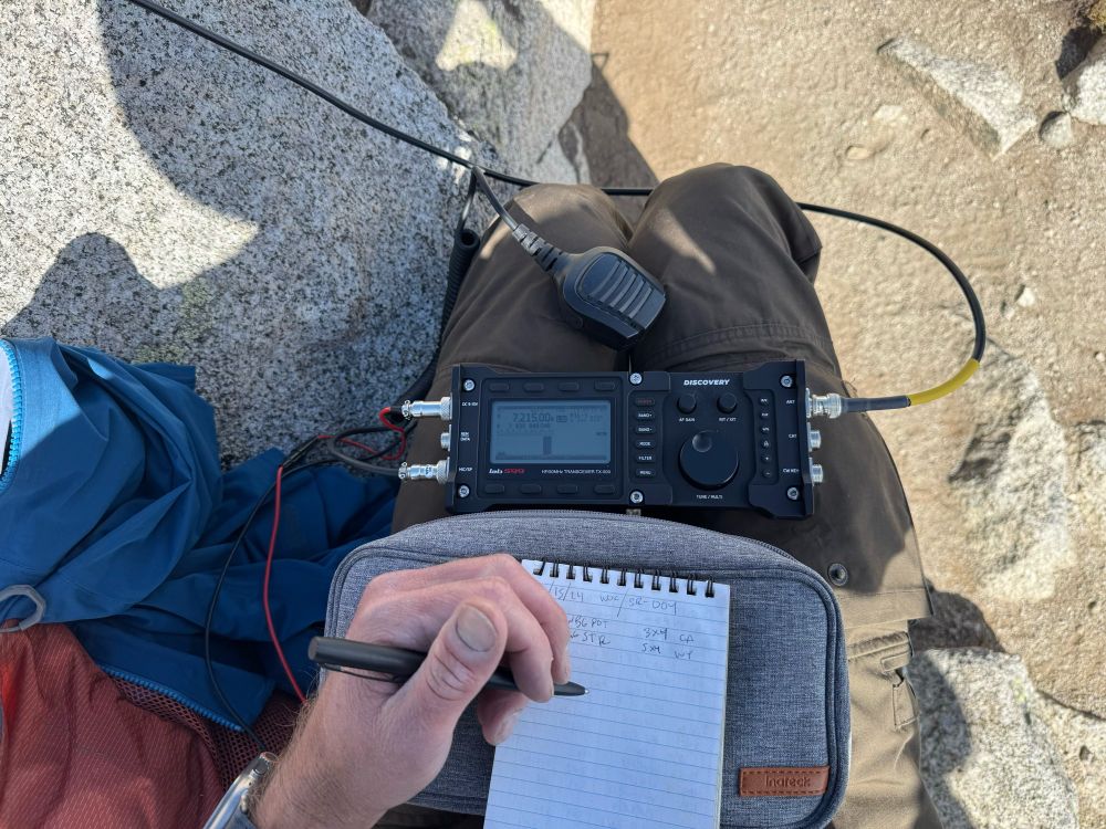 POV looking at a ham radio and log book, the authors writing hand in view