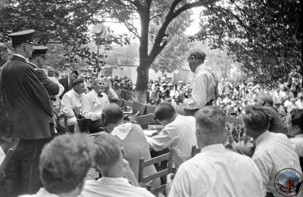 Darrow (standing, back to camera) questions Bryan (in bowtie)